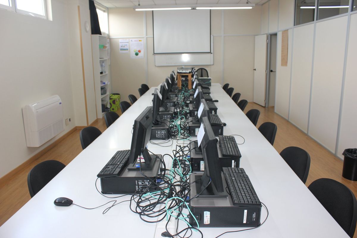 Aula de informática vista desde el fondo con proyector